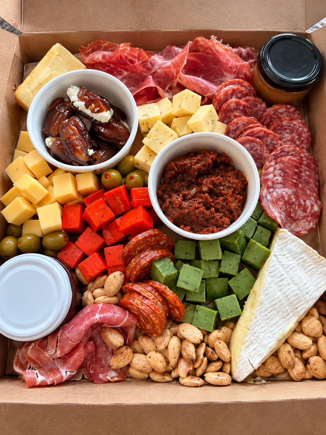 A welcome box of cured meats, cubed cheeses, brie, stuffed dates, olives and almonds